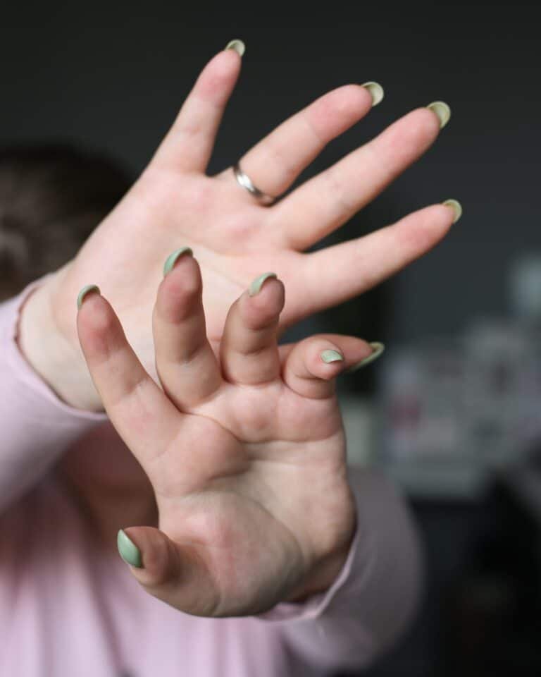 Close-up of a hand with brat green nail art, illustrating the brat green beauty trend
