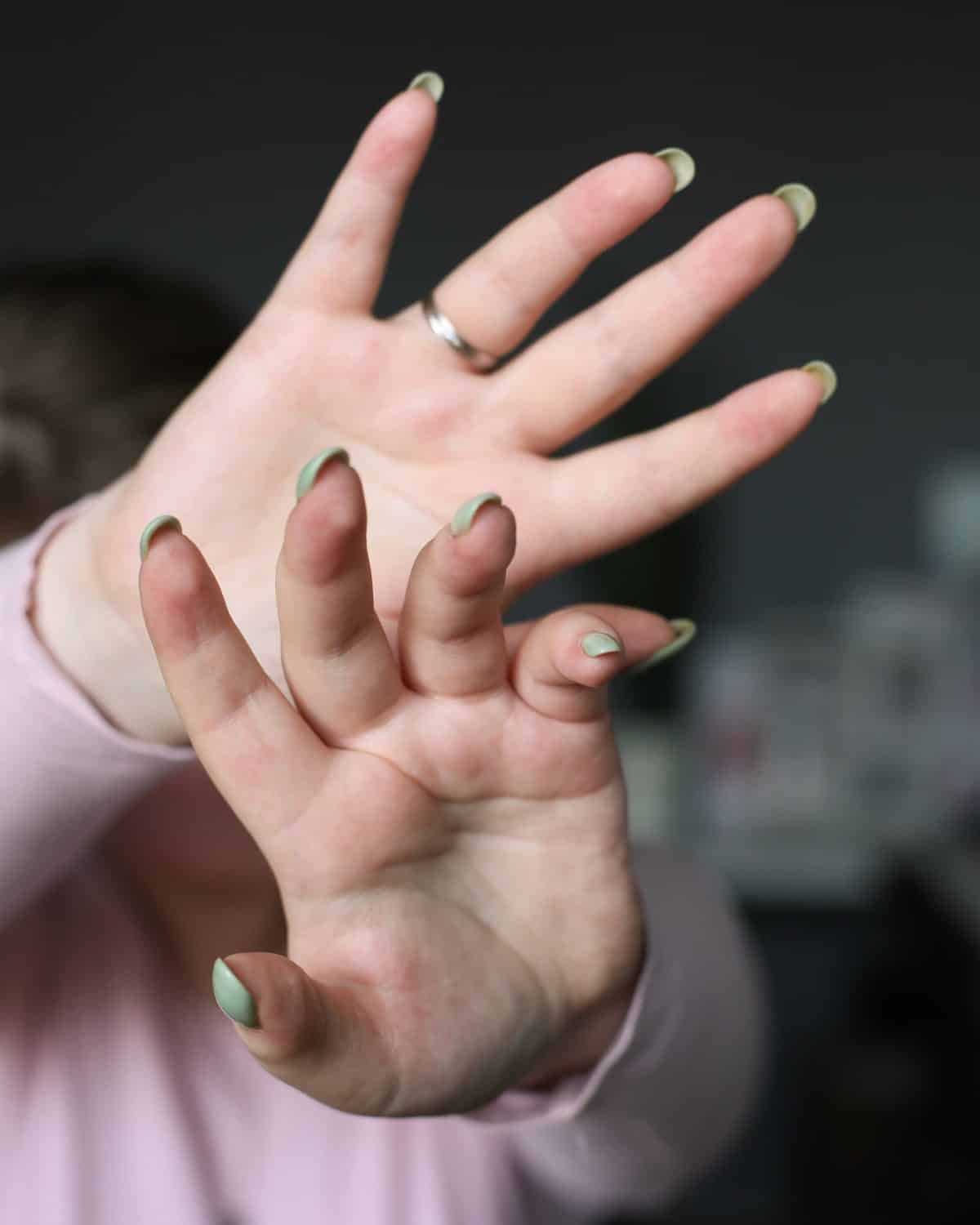 Close-up of a hand with brat green nail art, illustrating the brat green beauty trend